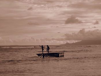 People on boat in sea against sky during sunset