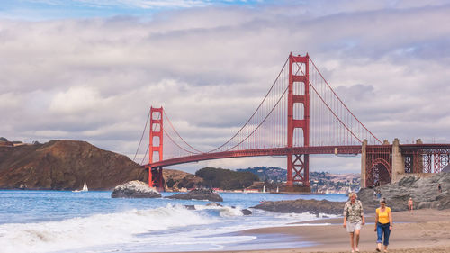 Golden gate bridge over sea against cloudy sky