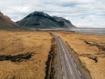 Scenic view of road by mountains against sky