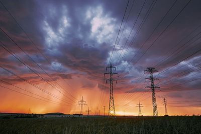 Electricity pylon on field against sky during sunset