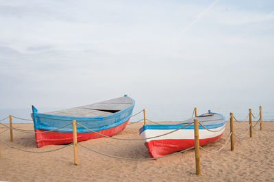 Boat moored on beach against sky