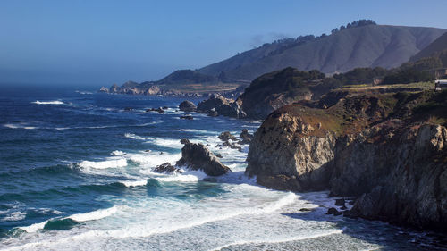 Scenic view of sea and mountains against clear sky