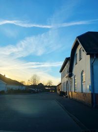 Empty road by buildings against blue sky