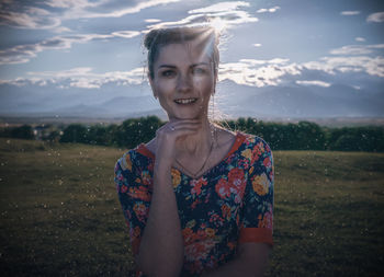 Portrait of a smiling young woman standing against sky