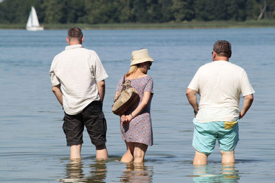 Rear view of friends standing by lake