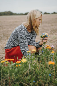 Woman picking flowers on field