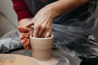 Close up of woman hands molding clay mug spinning on pottery wheel. potter hands forming clay cup