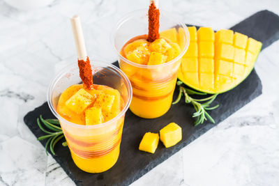 Mangonada drink made from mango and tajin chili powder in plastic glasses on the table. 