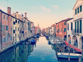 Boats on canal amidst buildings in chioggia