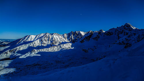 Scenic view of snowcapped mountain against blue sky