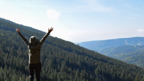 Rear view of person standing on mountain against sky