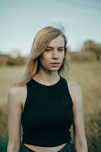 Portrait of young woman standing on field