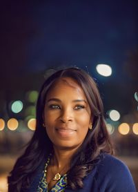 Portrait of young woman standing against illuminated lights