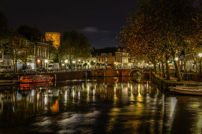 Illuminated bridge over river in city at night