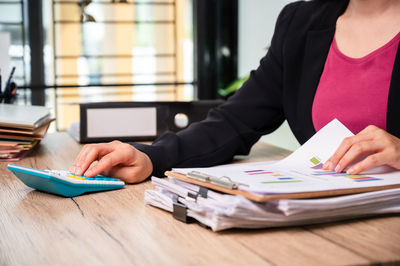 Midsection of woman reading book on table