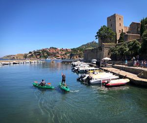 Boats in sea against clear blue sky