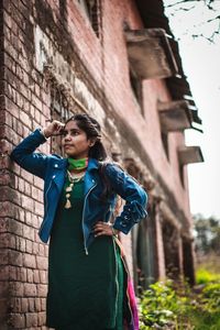 Young woman standing against wall