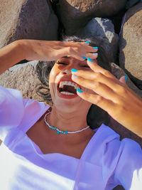 High angle view of woman laughing on rock