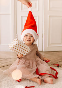 A cheerful emotional little child girl in red santa claus hats is having fun on christmas holiday