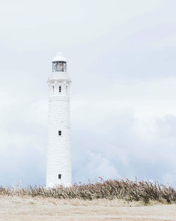 Lighthouse by sea against sky