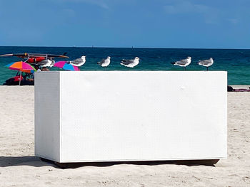 Deck chairs on beach against blue sky