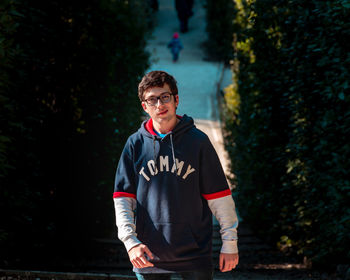 Portrait of young man standing against trees