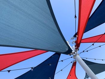 Low angle view of red and blue sun sail against clear sky