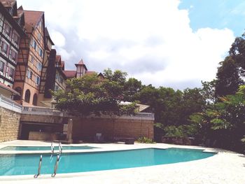 Swimming pool by building against sky