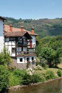 House by trees and buildings against sky