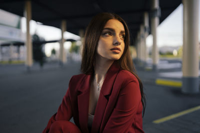 Woman in a red suit sitting at the bus station