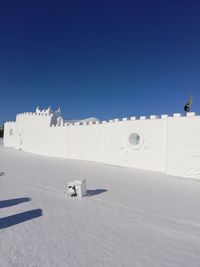 Scenic view of snow covered land against clear blue sky