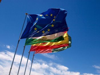 Low angle view of flags against blue sky