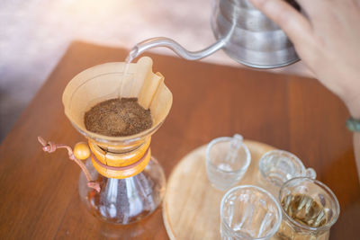 Cropped hand of person pouring drink on table