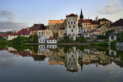 Residential buildings by lake against sky