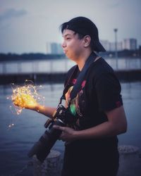 Side view of young woman standing by sea at night