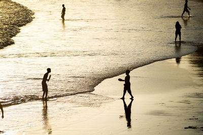 People walking on the sand of rio vermelho beach in the late afternoon.
