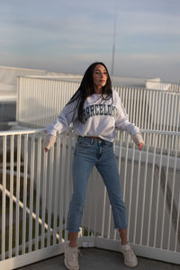 Portrait of young woman standing against wall