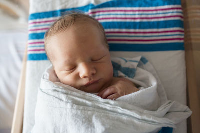 Close-up of baby boy sleeping in crib at hospital