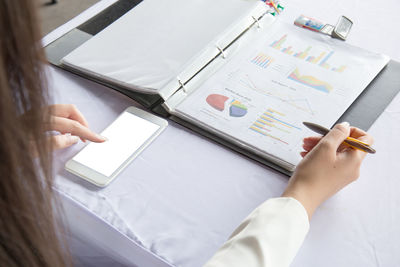 High angle view of businesswoman using mobile phone on desk