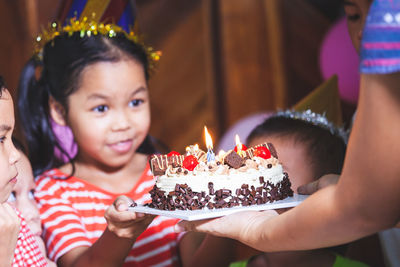 Midsection of mother and girl holding cake