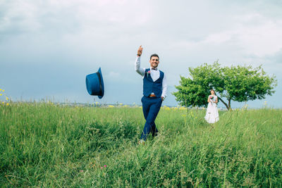 Full length of friends standing on field against sky