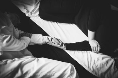 Couple holding hands while sleeping on bed at home