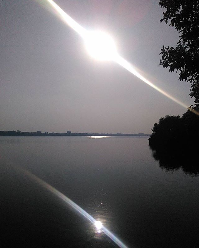 water, sun, tranquil scene, tranquility, scenics, reflection, beauty in nature, sunbeam, sunlight, sky, nature, lens flare, lake, idyllic, sea, waterfront, tree, bright, outdoors, non-urban scene