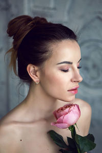 Portrait of a beautiful attractive woman in a gray towel in the bathroom holding a red rose