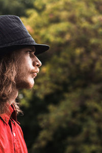 Young man wearing hat looking away while standing outdoors