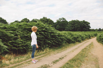 Side view of young woman standing on footpath