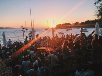 People enjoying at party by sea during sunset