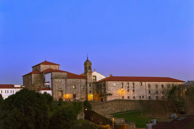 Illuminated buildings against clear blue sky