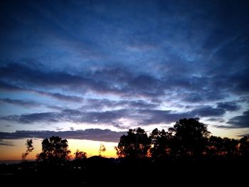 Silhouette trees against dramatic sky during sunset