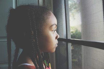 Side view of girl looking through window